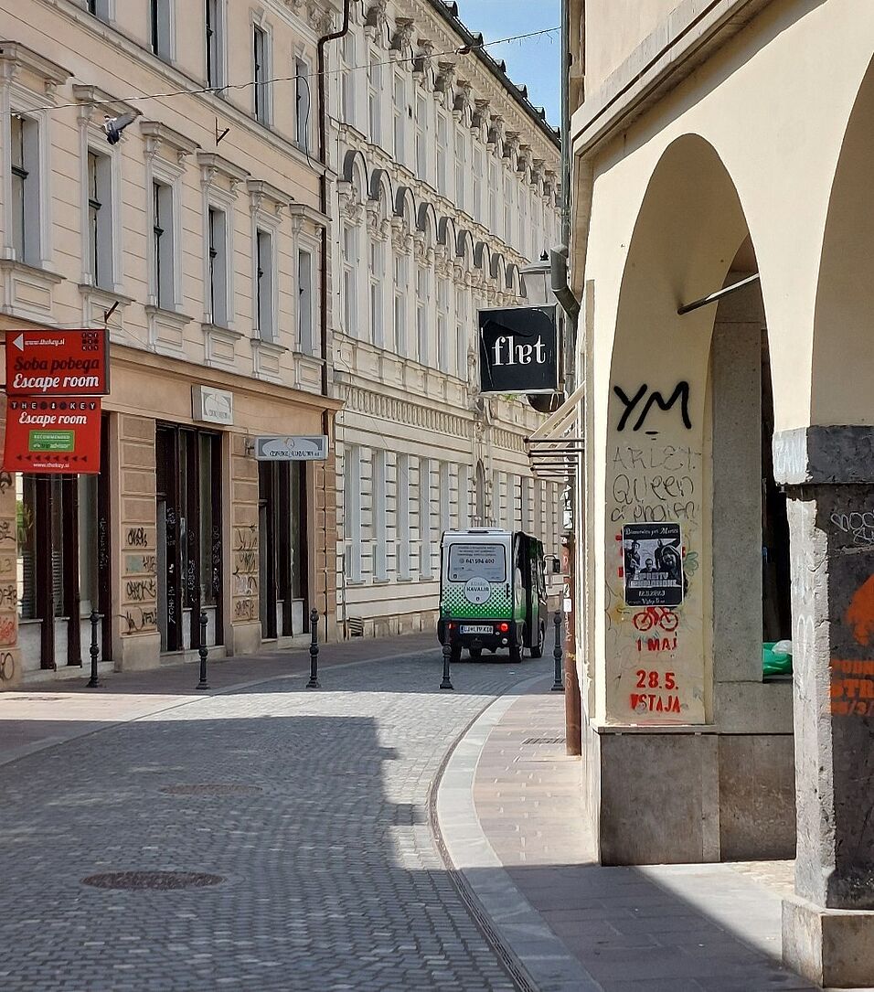 “Kavalir” (electric micro busses) driving through the streets and the distinct bicycle stencil, a political graffiti used as symbol for protests against then prime minister Janez Janša (©Thurner, 2023) 
